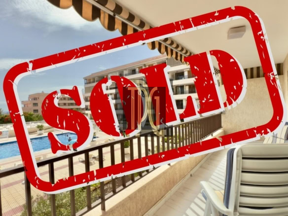Balcony view of a resort with a pool area in the background, overlaid by a bold red SOLD stamp indicating the property is sold.