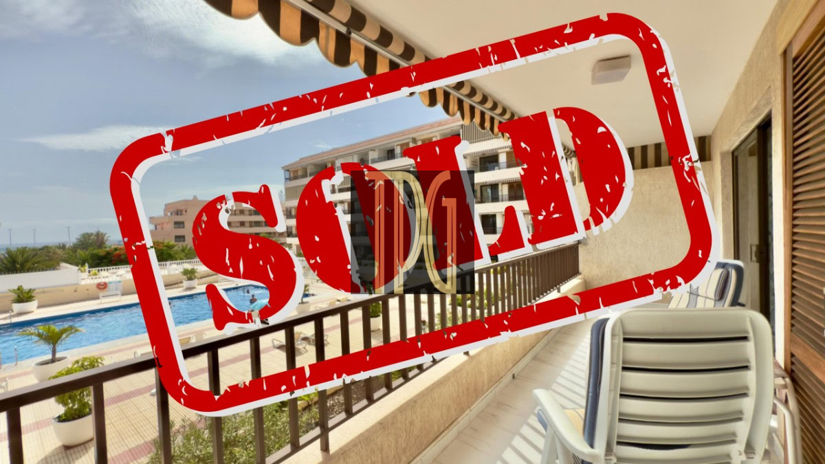 Balcony view of a resort with a pool area in the background, overlaid by a bold red SOLD stamp indicating the property is sold.