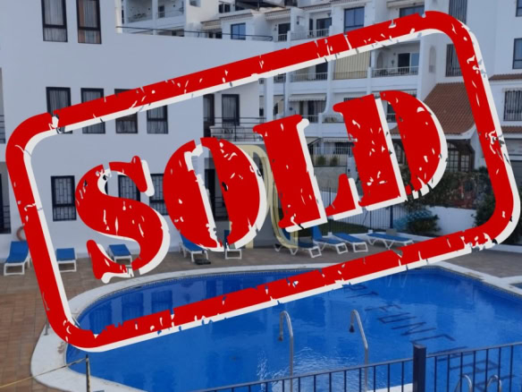Swimming pool in a residential complex with blue water and white buildings, overlaid by a large red 'SOLD' stamp indicating the property is sold.