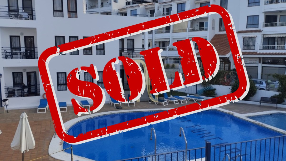 Swimming pool in a residential complex with blue water and white buildings, overlaid by a large red 'SOLD' stamp indicating the property is sold.