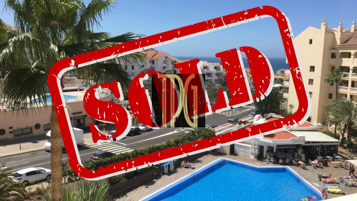 SOLD1939 Resort-style pool area with palm trees and white buildings, overlaid by a large red 'SOLD' stamp indicating the property is sold.