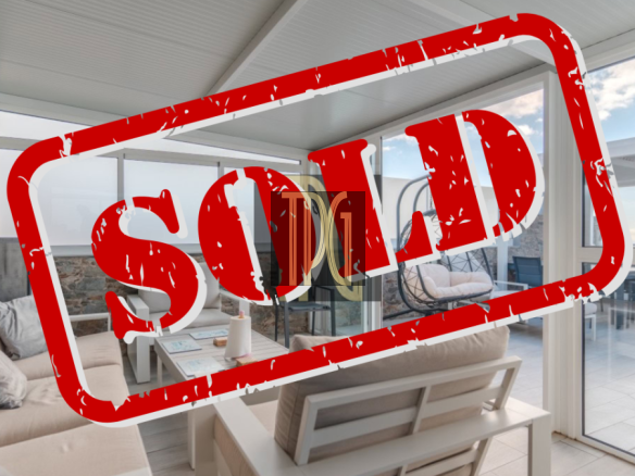 Bright modern living room with beige sofa and large windows, a red SOLD stamp across the scene.