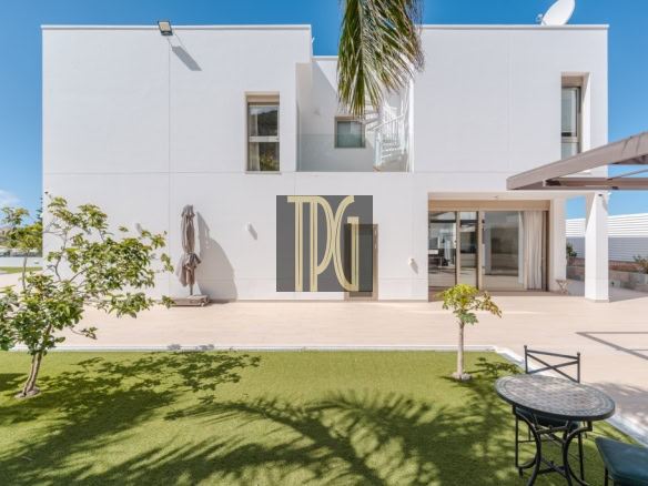 Modern white two‑story house with a spacious patio, lawn, and a large TDG logo on the central door panel.