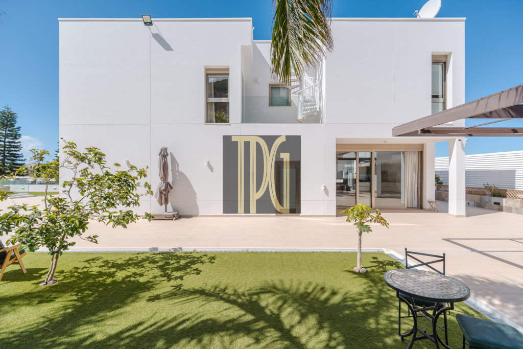 Modern white two‑story house with a spacious patio, lawn, and a large TDG logo on the central door panel.