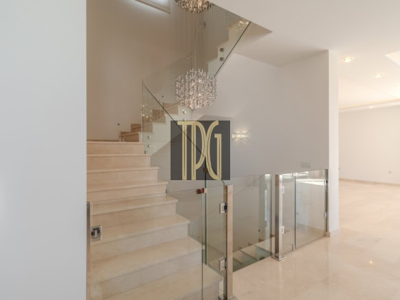 Modern two-story foyer with a beige marble staircase, glass railings, and a crystal chandelier.
