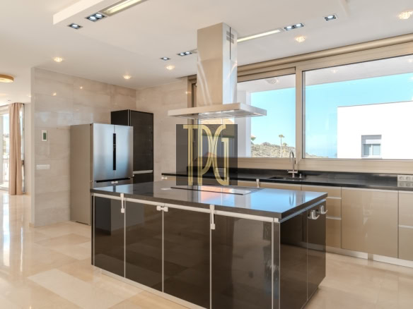 Modern kitchen with a black island, stainless steel refrigerator, and a large windowed wall showing outdoor light.
