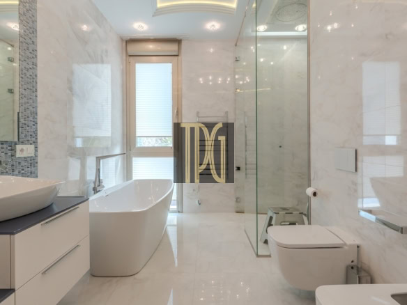 Modern white bathroom with a freestanding tub, double vanity, glass shower, and wall-mounted toilet.
