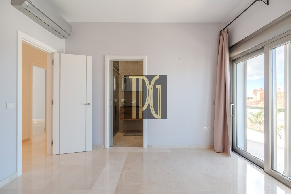 Bright, empty living room with beige glossy tile floor, sliding glass doors to a balcony on the right, and a doorway to a bathroom in the center.