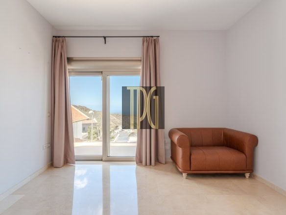 Minimalist living room with a sliding glass balcony door, pink curtains, and a brown leather loveseat on the right panel wall.