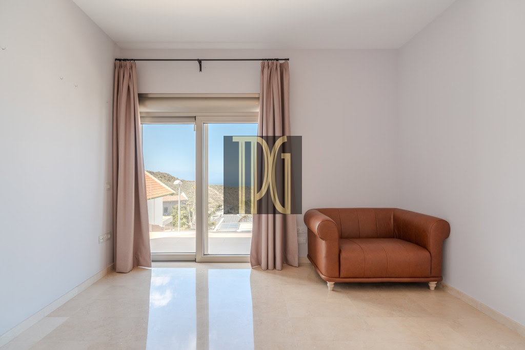 Minimalist living room with a sliding glass balcony door, pink curtains, and a brown leather loveseat on the right panel wall.