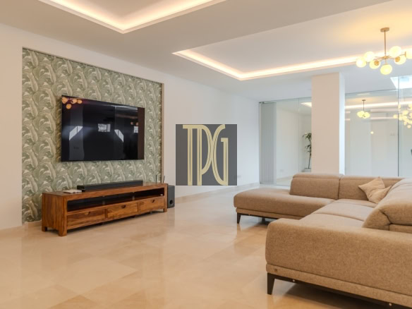 Modern living room with a mounted TV on a palm-pattern accent wall and a wooden media console beneath it.