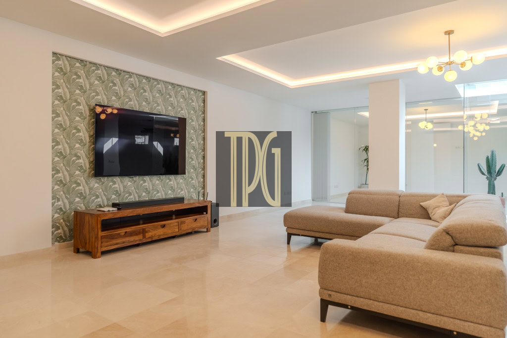 Modern living room with a mounted TV on a palm-pattern accent wall and a wooden media console beneath it.
