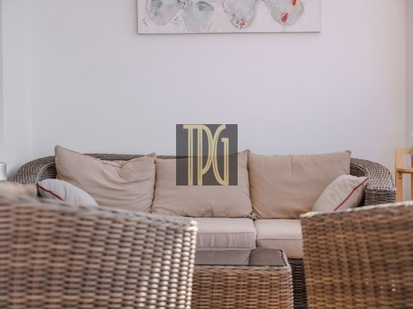 Cozy wicker sofa set with beige cushions in a bright living room, with a glass coffee table and a potted plant on the side table.