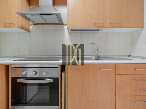 Modern kitchen with wood cabinets, stainless oven, and a double sink along a tiled backsplash on white counter.