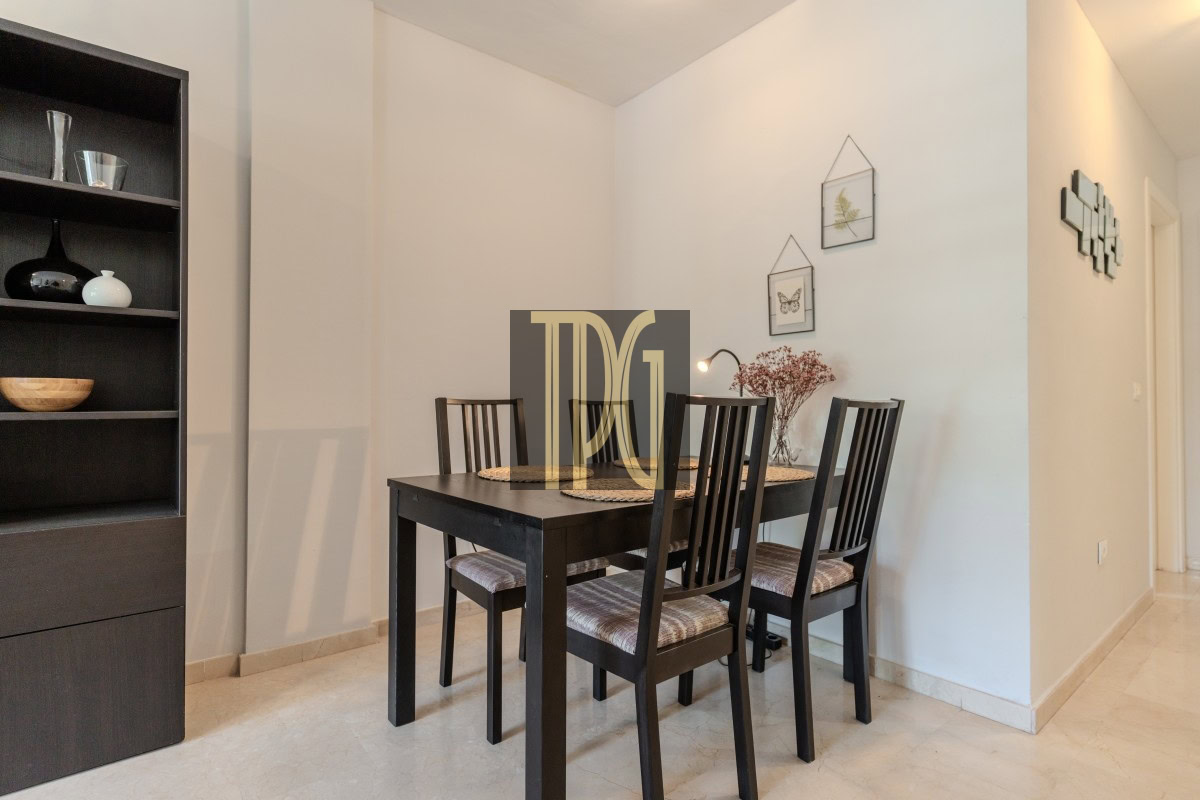 Dining room with a dark wooden table and four chairs, a tall black shelving unit on the left, and light walls.