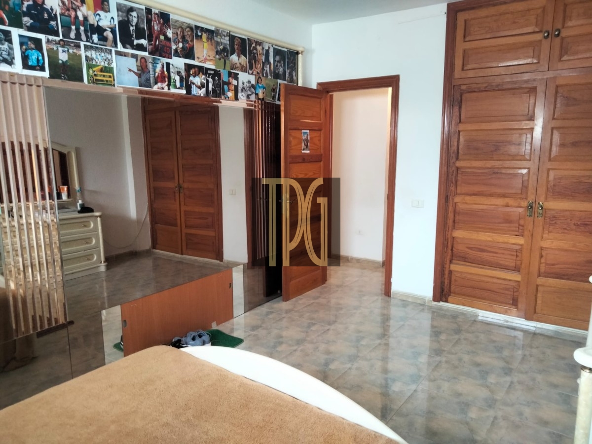 Bedroom with tiled floor, wooden wardrobes, and a photo collage strip along the top edge above a doorwayed area.
