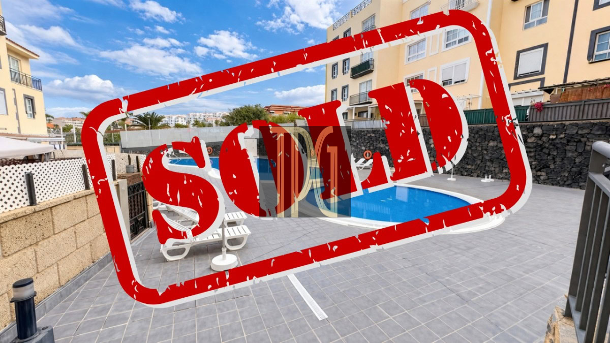 Outdoor pool area of a residential complex with a large red SOLD stamp across the image.