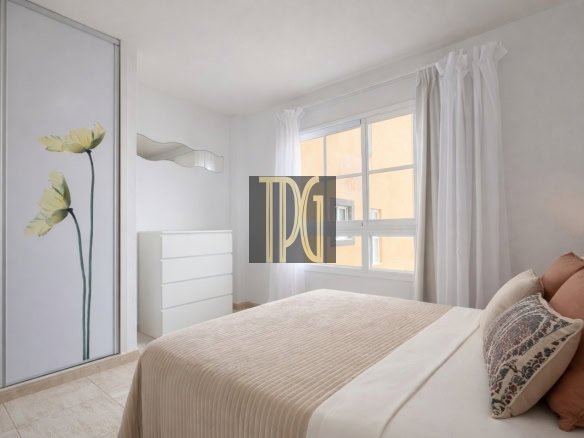 Bright minimalist bedroom with white dresser, wavy mirror, and a sliding door with a floral panel in soft tones.