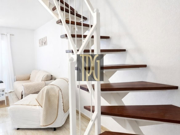 White metal staircase with dark wooden steps beside a beige living room area.