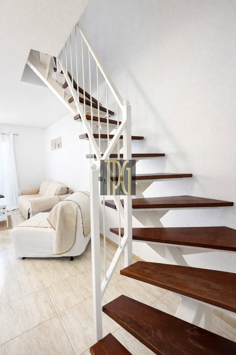 White metal staircase with dark wooden steps beside a beige living room area.