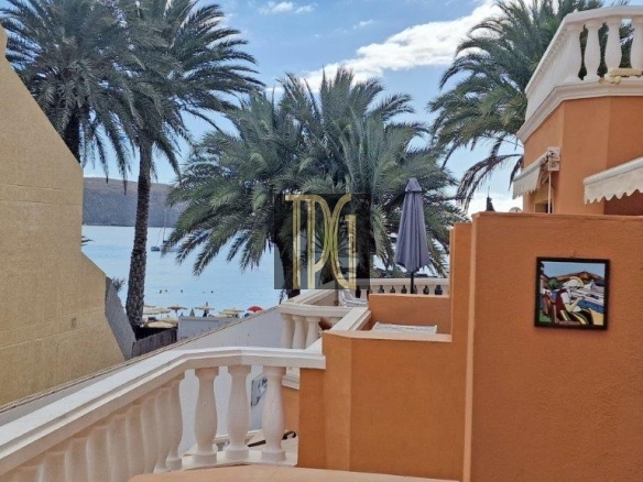Orange Mediterranean-style terrace with white railing and palm trees, overlooking the sea.