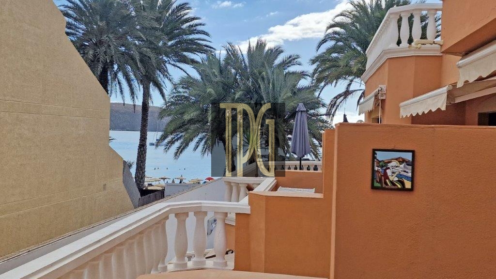 Orange Mediterranean-style terrace with white railing and palm trees, overlooking the sea.