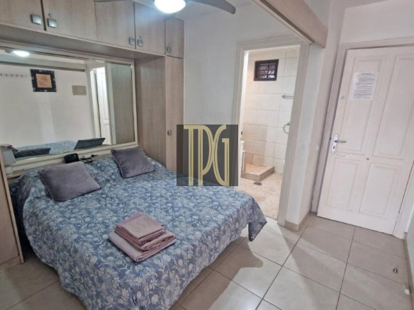 Double bed with blue floral bedspread and folded towels on top; built-in wardrobe with a mirror behind, and a bathroom doorway to the side.