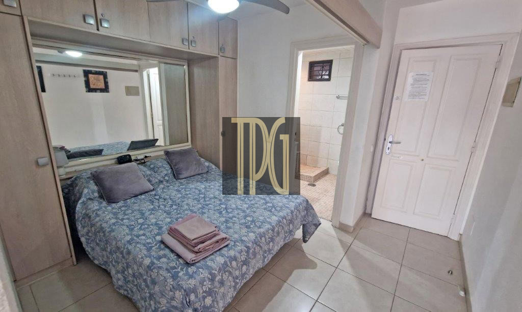 Double bed with blue floral bedspread and folded towels on top; built-in wardrobe with a mirror behind, and a bathroom doorway to the side.