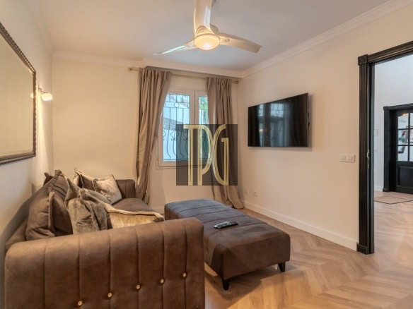 Cozy living room with a brown sectional sofa and matching ottoman facing a wall-mounted TV on the right.