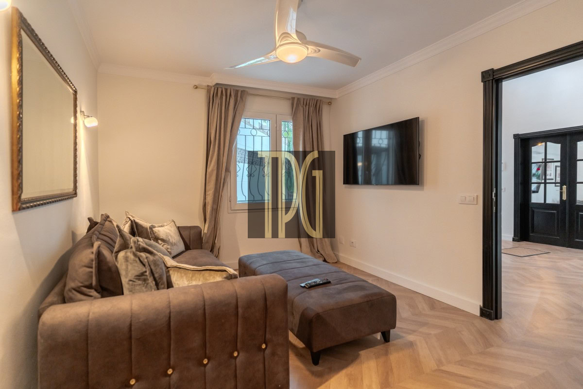 Cozy living room with a brown sectional sofa and matching ottoman facing a wall-mounted TV on the right.