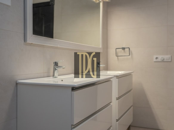 Modern bathroom vanity with two white sinks, chrome faucets, and a large wall mirror in a neutral-toned tile room.