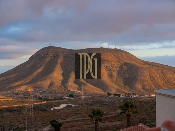 Desert hillside at dusk with a small town at the base and power lines; a large DGI watermark sits in the center.