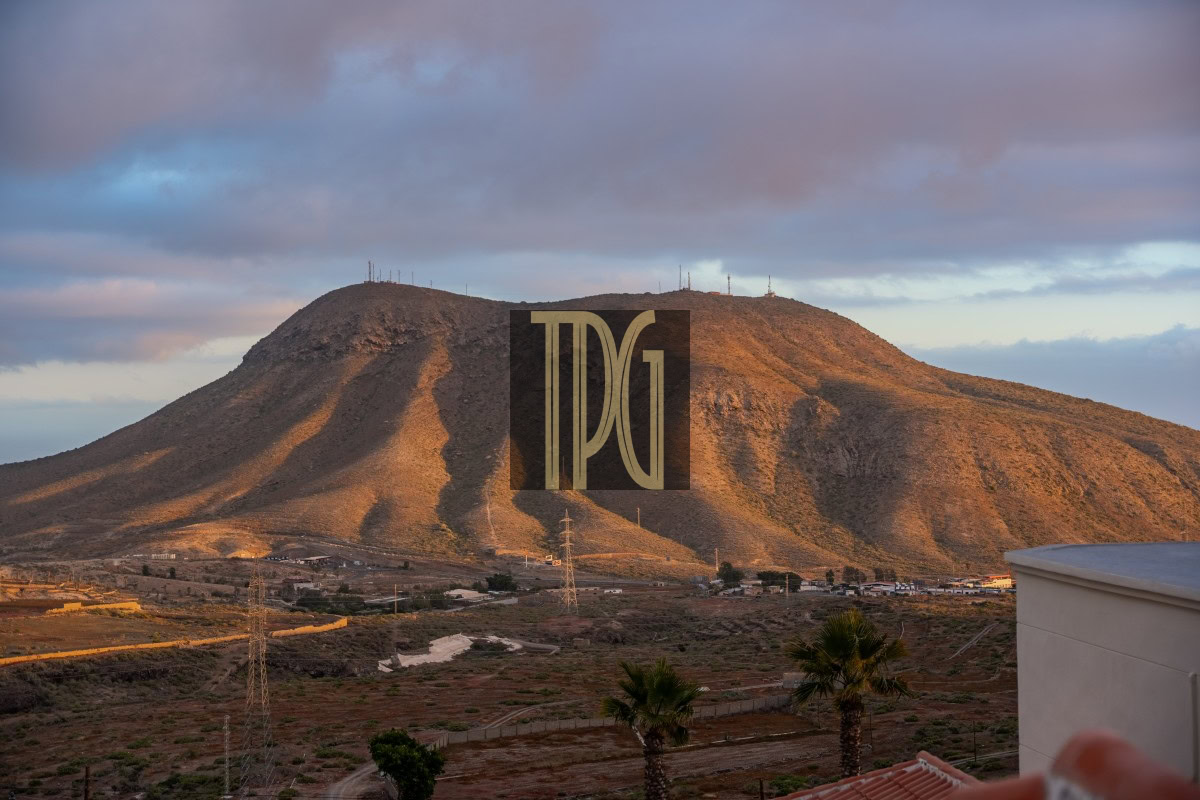 Desert hillside at dusk with a small town at the base and power lines; a large DGI watermark sits in the center.