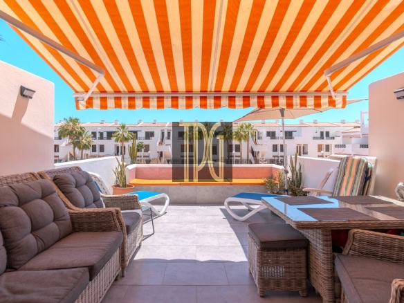Rooftop patio with an orange-and-white striped awning, wicker couches, and a glass-topped dining table.