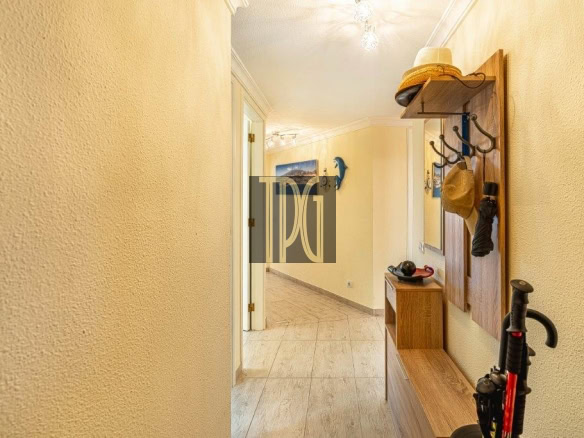 Bright yellow hallway with a wooden coat rack, hanging hats, and a small bench along the wall; doorway in the distance.