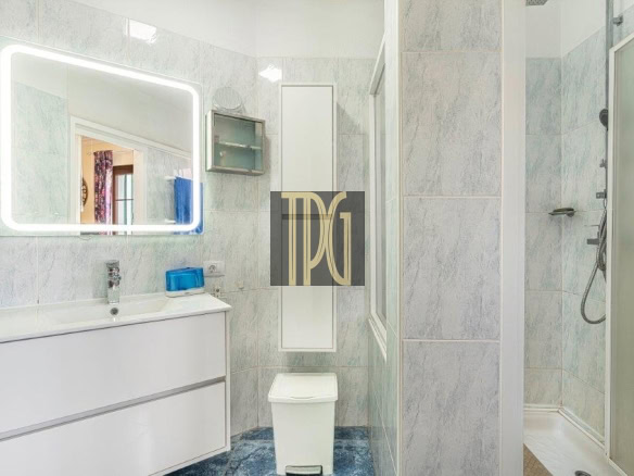 Bright modern bathroom with a backlit rectangular mirror above a white vanity and sink, blue accents, and a toilet nearby.