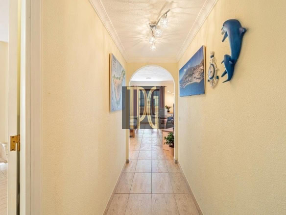 Bright beige hallway with tiled floor, archway at end, and seaside wall decor including a blue dolphin sculpture on the right.