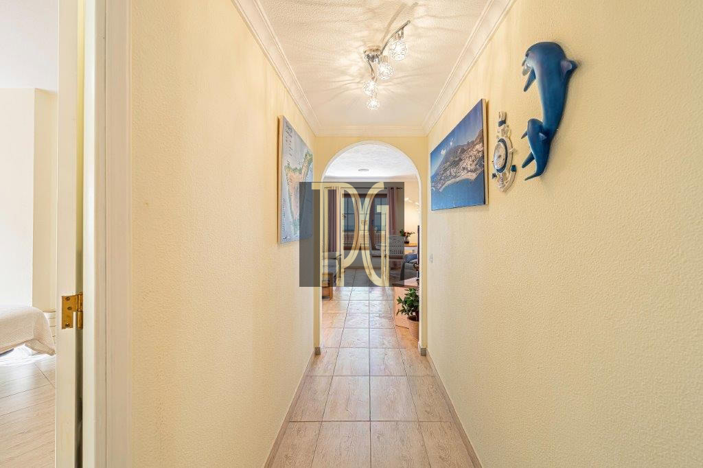 Bright beige hallway with tiled floor, archway at end, and seaside wall decor including a blue dolphin sculpture on the right.