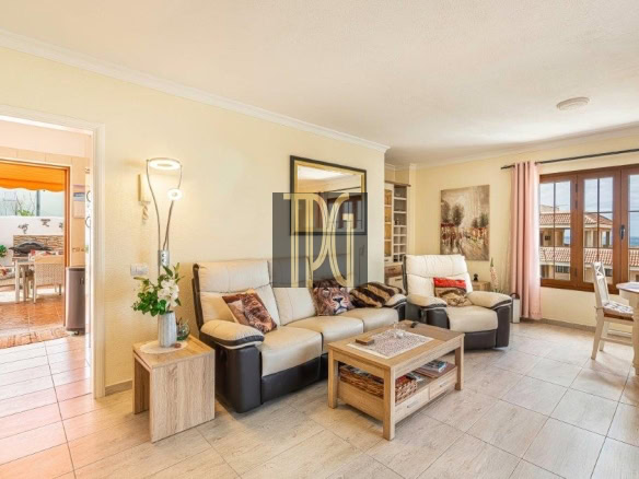 Bright living room with cream leather sofas, a wooden coffee table, and large windows opening to a sunny patio.