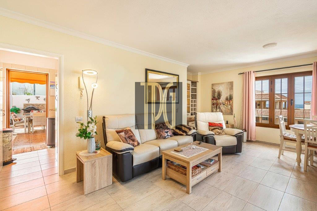 Bright living room with cream leather sofas, a wooden coffee table, and large windows opening to a sunny patio.