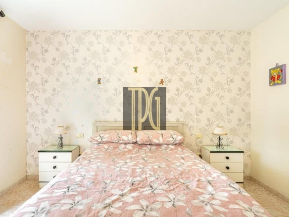 Cozy bedroom with a pink floral bedspread, a white headboard, and matching nightstands on each side of the bed.