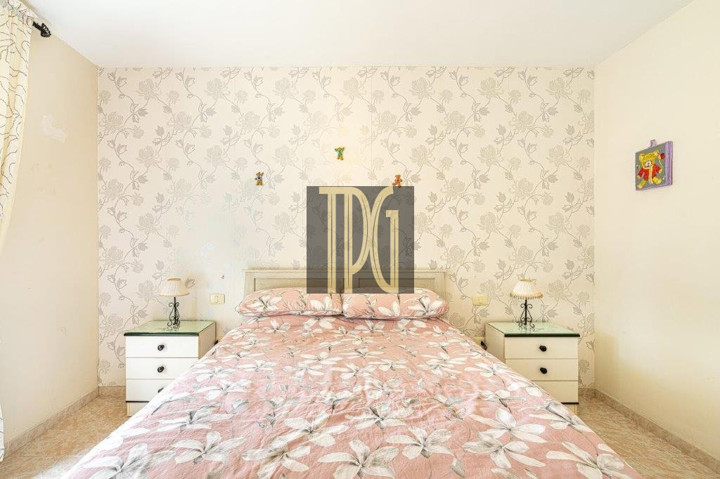 Cozy bedroom with a pink floral bedspread, a white headboard, and matching nightstands on each side of the bed.