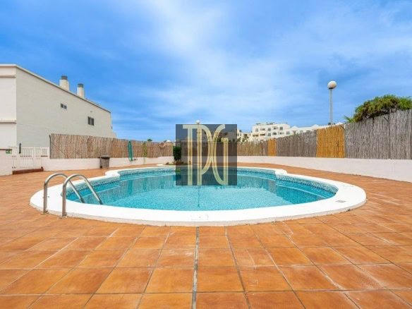 Circular pool on a terracotta-tiled deck with a metal ladder, white coping, and surrounding wooden fence under a blue sky.