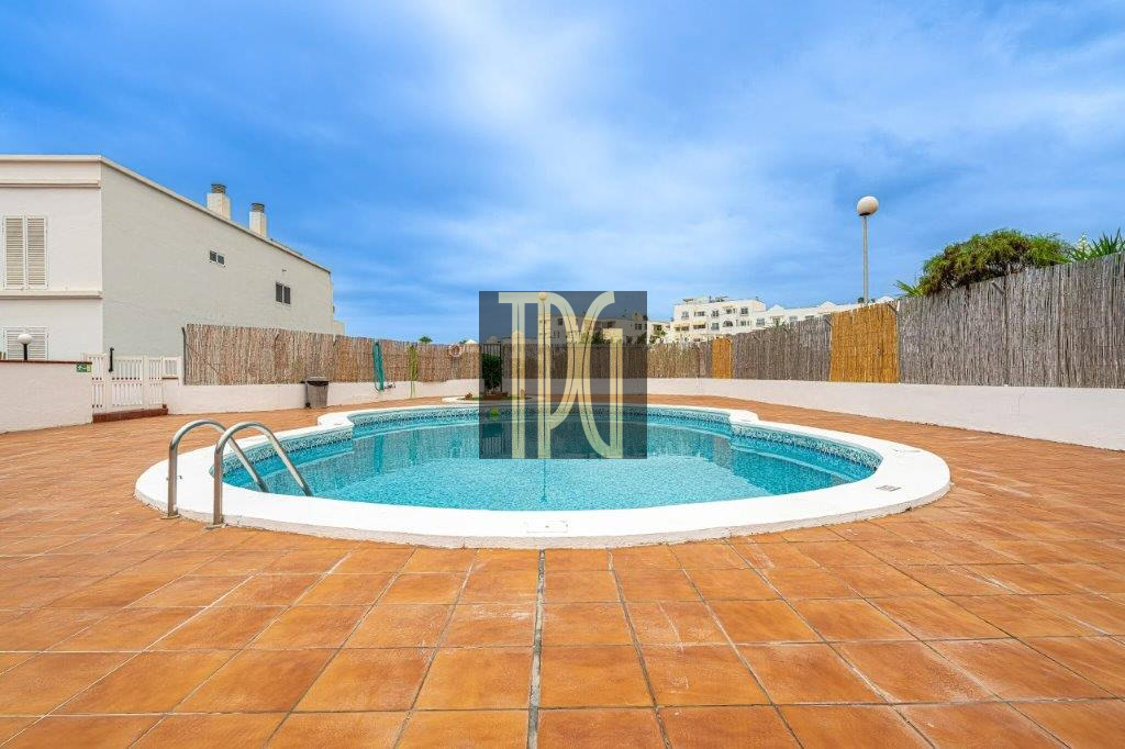 Circular pool on a terracotta-tiled deck with a metal ladder, white coping, and surrounding wooden fence under a blue sky.