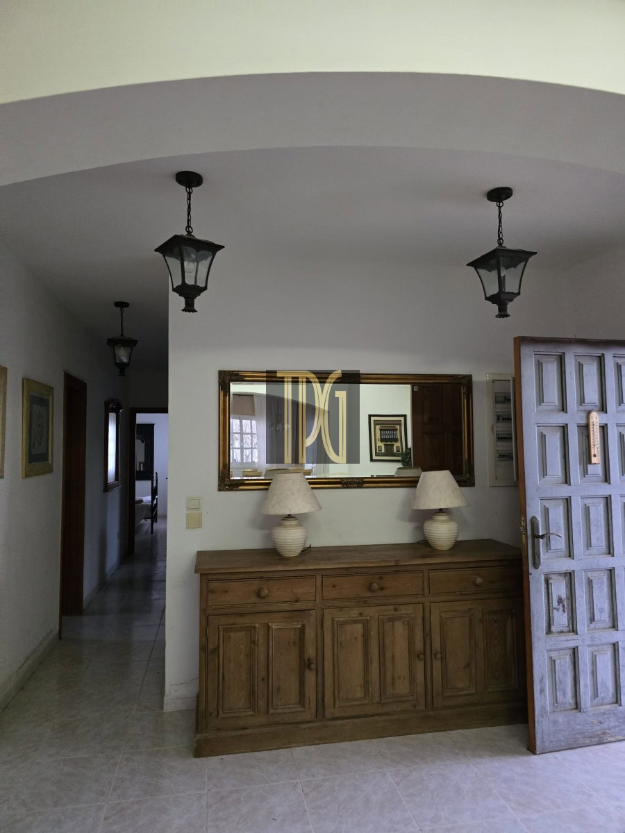 Interior foyer with a wooden sideboard, two ceramic lamps, and a large gold-framed mirror above the cabinet.