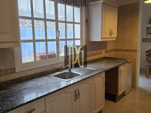 Bright kitchen with white cabinets, granite countertop, and double sink under a large window with a blue-and-white checkered valance.