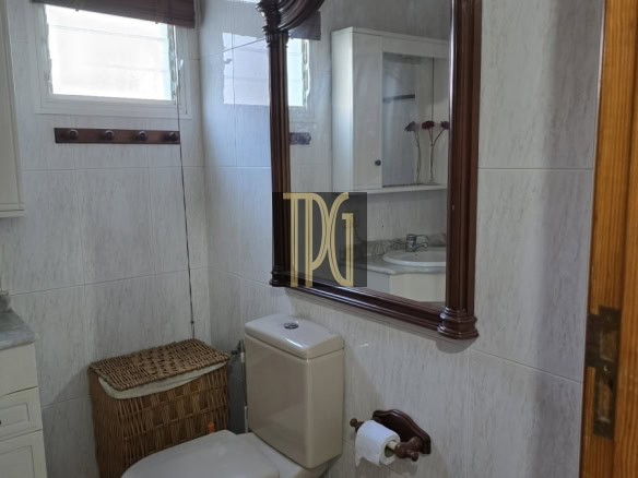 Ornate wooden-framed mirror over a beige toilet in a small tiled bathroom.