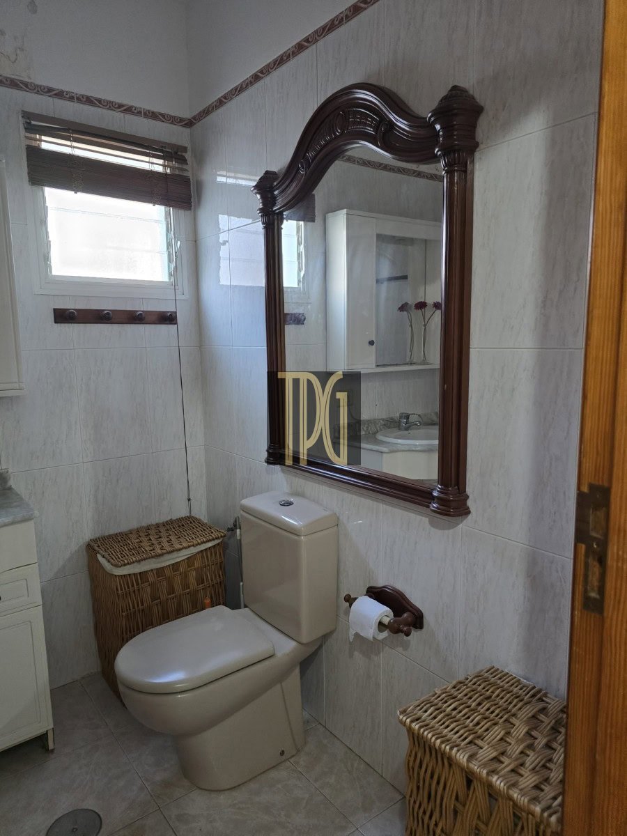 Ornate wooden-framed mirror over a beige toilet in a small tiled bathroom.