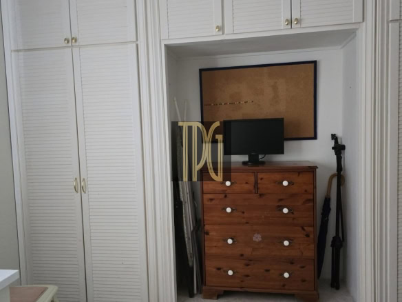 Built-in white closet alcove containing a wooden dresser with a small computer monitor on top and a corkboard above the dresser.
