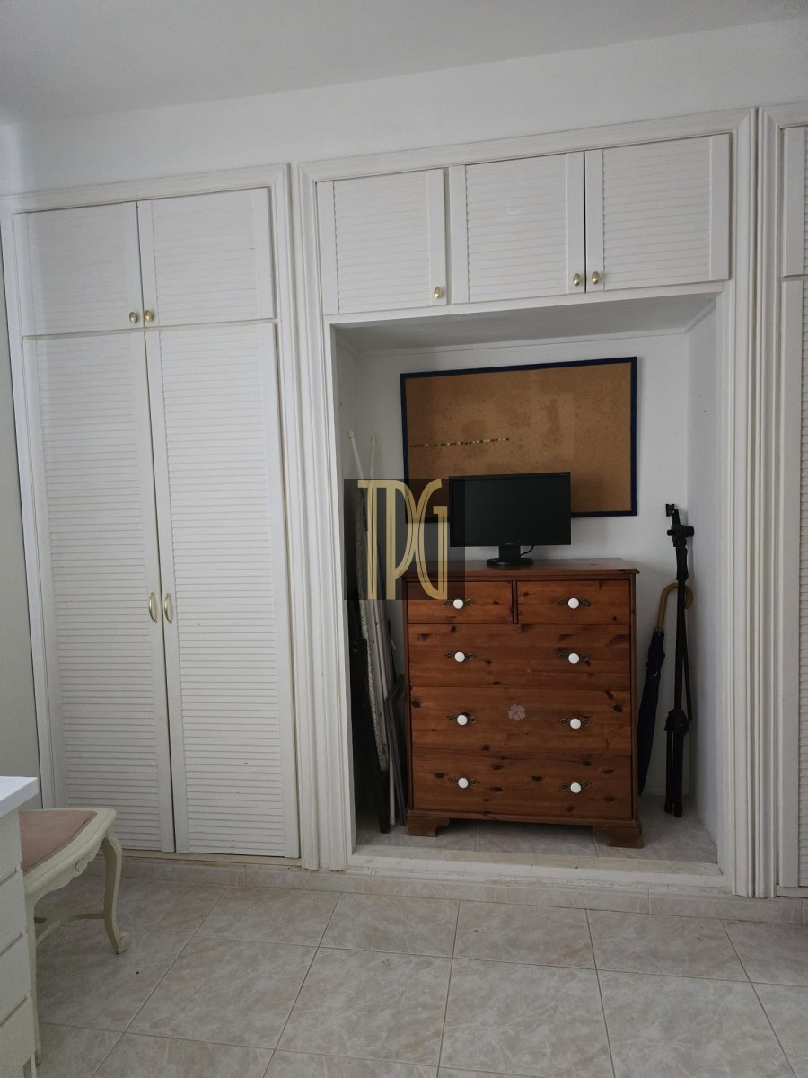 Built-in white closet alcove containing a wooden dresser with a small computer monitor on top and a corkboard above the dresser.